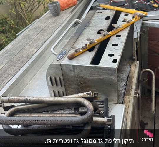 חלקי גריל מתכתיים וכלי עבודה על שולחן עבודה